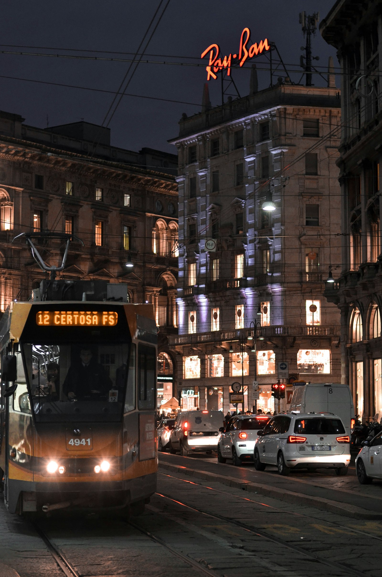 Strada di Milano di notte con un tram giallo e le insegne luminose